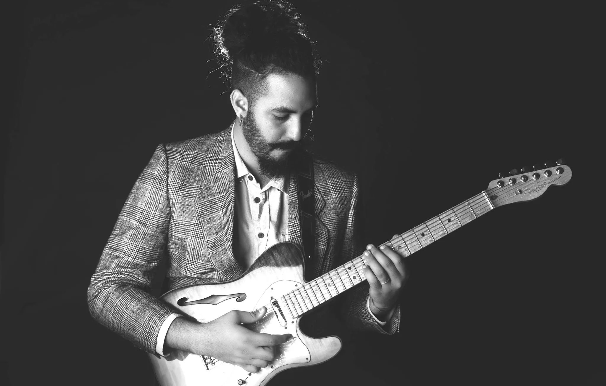 Ricky Castillo holding his electric guitar in a black-and-white artist portrait