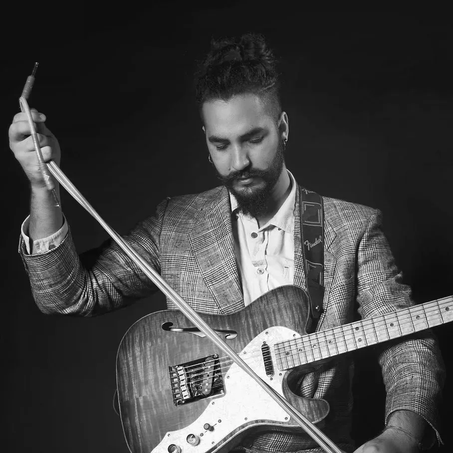 Ricky Castillo exploring guitar sounds with a bow in a black-and-white portrait